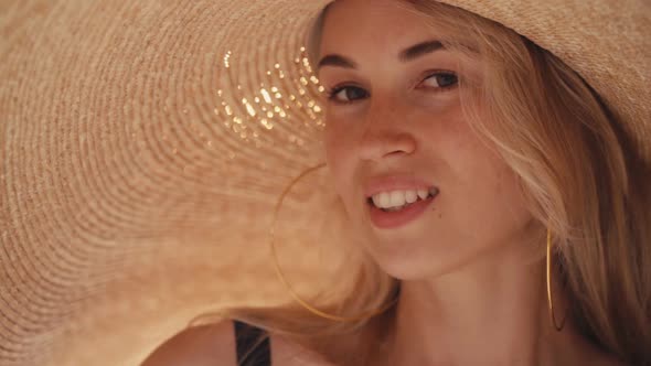 Beautiful Girl Wearing Big Straw Summer Hat on the Beach