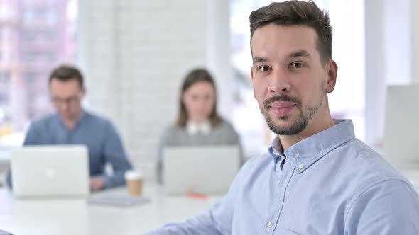 Attractive Young Man Smiling at the Camera in Office