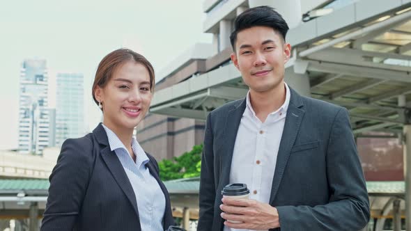 Asian young office business people stand outdoor in city with confident face holding hot coffee.