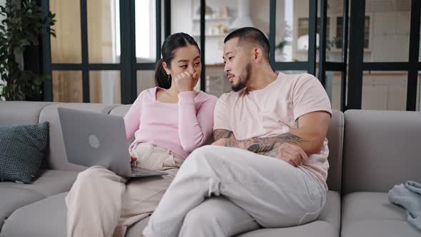 Asian Couple Sits Searching Information on Laptop Discussing