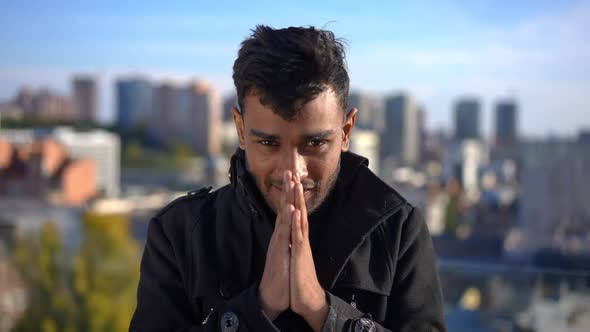 Front View Hoping Smiling Middle Eastern Man with Hands Together Looking at Camera in Sunshine