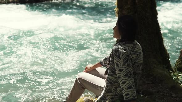 Woman Who Went for a Walk in the Park Sits Near a River and Looks at the Water