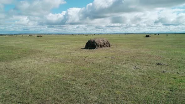 Aerial Low Altitude View of a Green Meadow with Haystacks