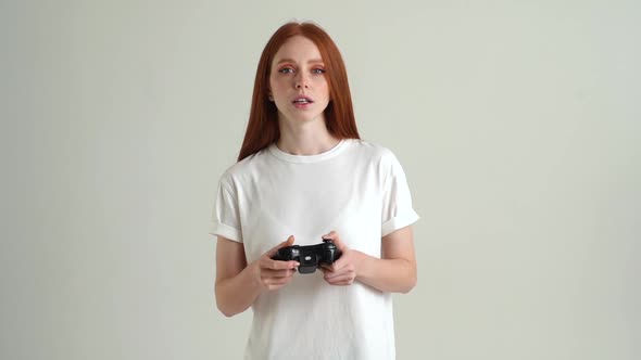 Portrait of Smiling Attractive Young Woman Playing Video Game with Controller on White Isolated