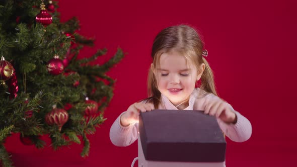 Christmas Miracle. Happy Little Girl Opening Xmas Gift with Magic Light Inside