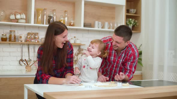 Smiling Parents with Small Daughter Having Fun with Flour in Kitchen