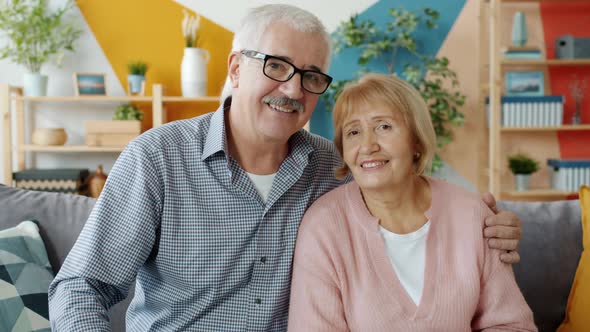 Portrait of Happy Retired People Couple Looking at Camera and Smiling at Home