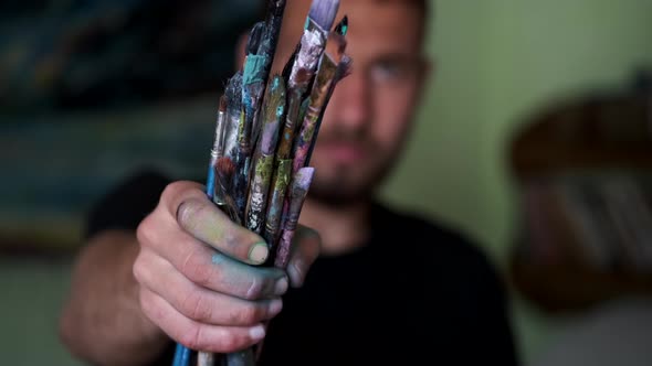 Artist Selecting and Dropping Paint Brushes on a Table