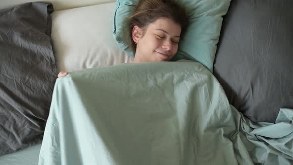 A young woman is basking in bed in the morning on a day off.