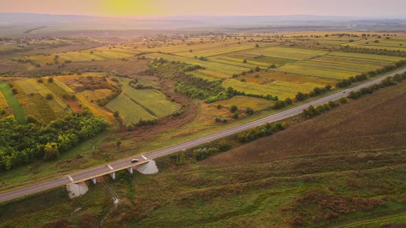 Aerial drone view of nature in Moldova at sunset. Wide fields, road with moving cars, trees