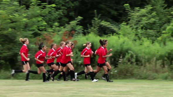Girl soccer players running, one girl trails behind
