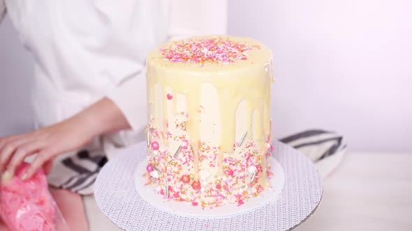 Step by step. Dripping a white chocolate ganache on birthday cake with white buttercream icing.