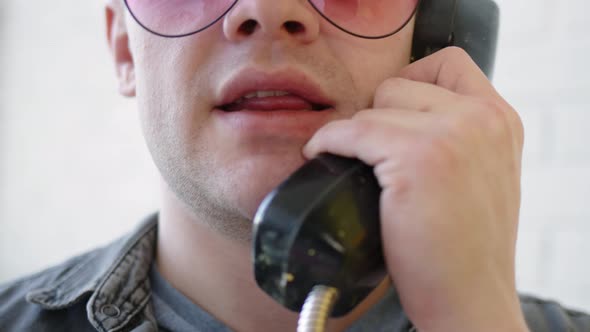 Close Up Happy Man in Pink Glasses Talking on Phone in Yellow Telephone Booth