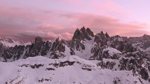 Rising drone shot of Candini Group Italian dolomites in winter beautiful pink sunset