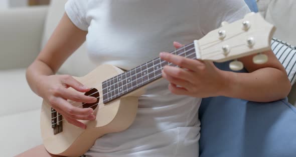 Woman practice ukulele at home