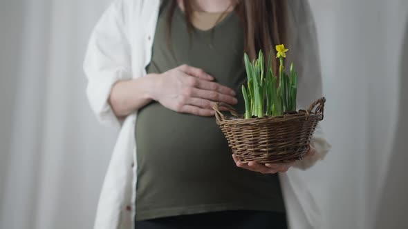 Front View Happy Unrecognizable Pregnant Woman Caressing Belly Holding Pot with Yellow Flowers