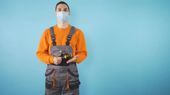 Young Professional Fixer with Covid 19 Mask and Screwdriver in Orange Clothes Isolated on Blue