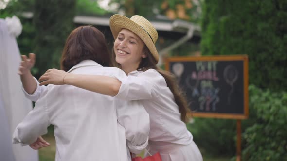 Young Woman and Teenage Girl Hugging Pregnant Friend Rejoicing Gifts on Backyard