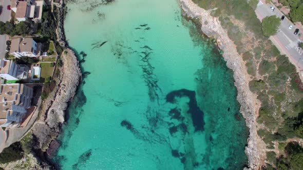 Flight above the crystal clear water to reveal a white sandy beach of Cala Marcal