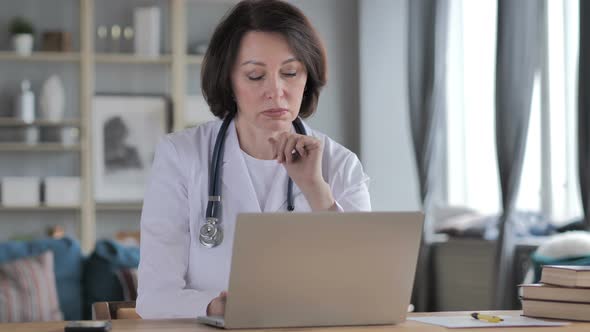 Old Lady Doctor Thinking While Working on Laptop