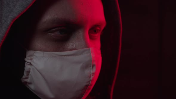 A Man in a Medical Mask and Hood Looks at the Camera