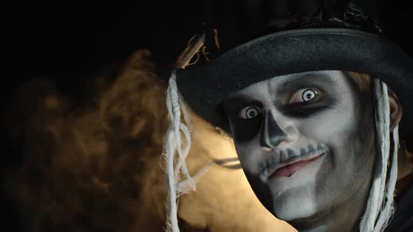 Frightening Man in Skeleton Halloween Makeup Turns Head and Looks Into Camera with Eyes Wide Open