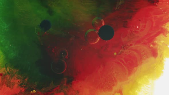 Very slowing colorful liquid with black dots in it. top shot