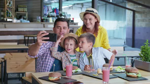 Attractive Parents, Man and Woman, Together with Their Male Children, Enjoy Family Dinner at Fast