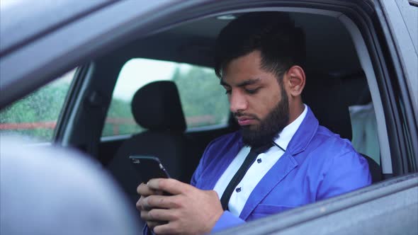 Muslim Man Sitting in the Driver's Seat in the Car and Typing on the Smartphone