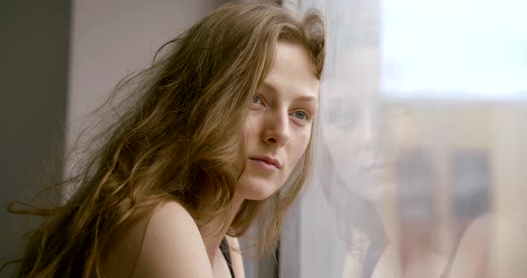 Portrait of a Pretty Girl Model Posing at a Large Panoramic Window. Face Close-up.