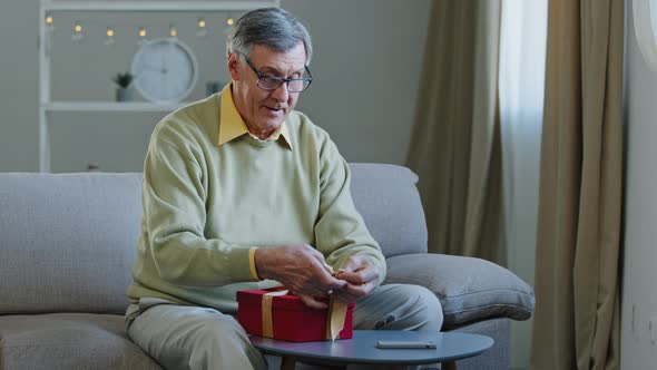 Happy Caucasian Old Man Grandfather Pensioner Wrapping Red Present Box Tying Ribbon