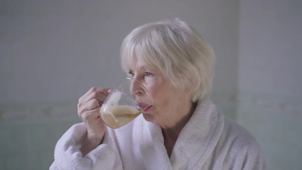 Beautiful Senior Woman with Grey Hair Drinking Coffee in Slow Motion Turning Looking at Camera