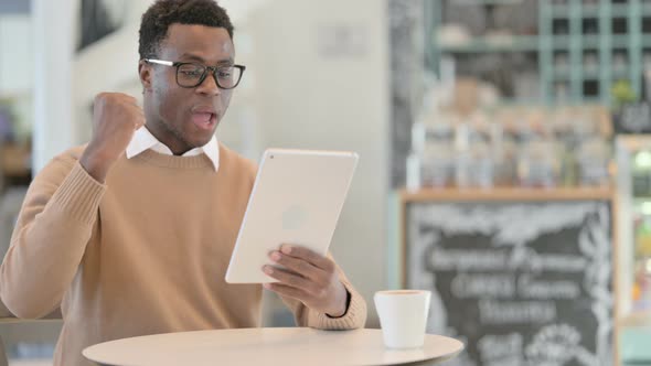 Successful Creative African Man Celebrating on Tablet in Cafe