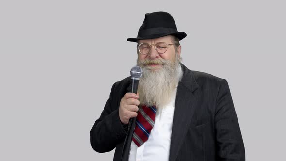 Smiling Old Senior Speaker with Long Beard Giving Speech with Microphone