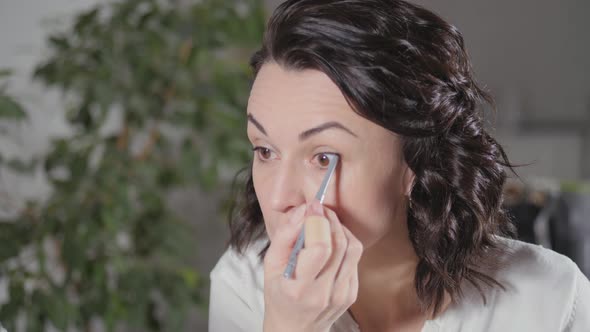 Applying the Morning's Makeup. The Brunette Creates a Face Drawing for Herself Before Leaving for