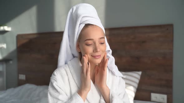 Attractive Woman in a Bathrobe After a Shower, Puts Cream on Her Face