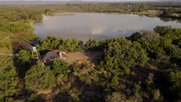 Secluded lakeside rural house with solar panel on roof, in countryside forested area. Aerial view