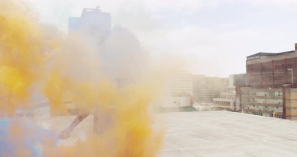 Fashionable young woman on urban rooftop using smoke grenades