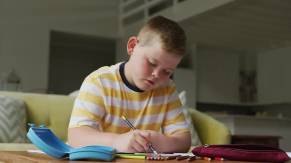 Caucasian boy sitting at table and learning alone at home