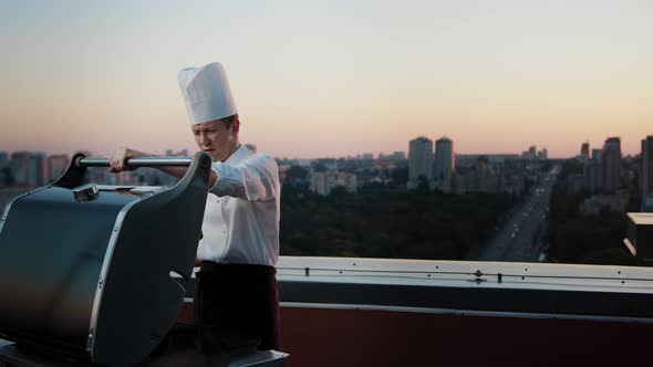 A professional Chef prepares a barbecue on the rooftop of a skyscraper. An expensive restaurant