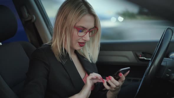 Happy Blonde Dials a Number and Talks on the Smartphone in the Car