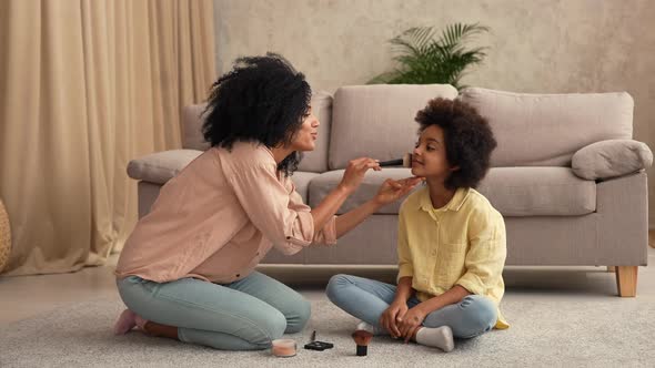 African American Woman Playing with Little Girl Using Makeup Brushes