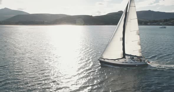 Sail Boat Yachting at Open Sea Harbor with Sun Reflection Aerial alt