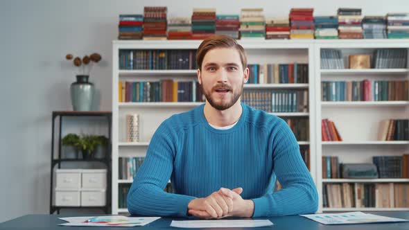 Young man sitting in home office, looking at camera, doing online job interview during video chat