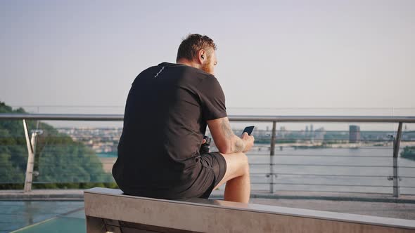 Man Checks Social Networks Sitting on Observation Deck