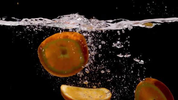 Slow Motion of Orange Slice Falling in Water Against Dark Background