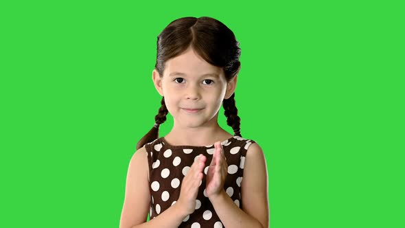 Little Girl in Polka Dot Dress Clapping Her Hands Looking at Camera on a Green Screen Chroma Key