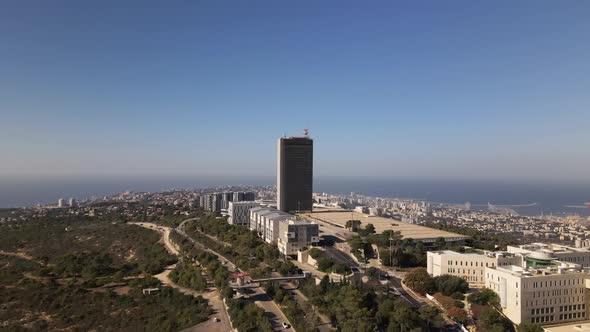 Drone flight of a high building on the outskirts of a city with a park and nature trails, Haifa, Isr