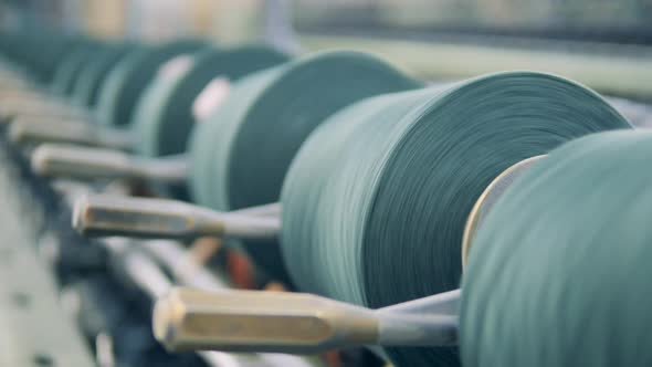 Thread Spools are Rotating in the Textile Machinery in a Close Up