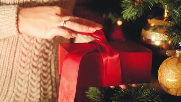 Closeup  Video of Young Woman Pulling Red Ribbon and Unwrapping Box with Christmas Gift